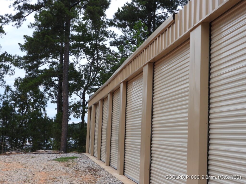 a self storage building with a metal wall and trees.